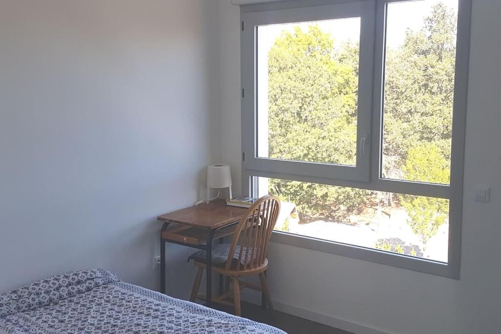 雷恩Appartement entier的一间卧室配有书桌、一张床和两个窗户。
