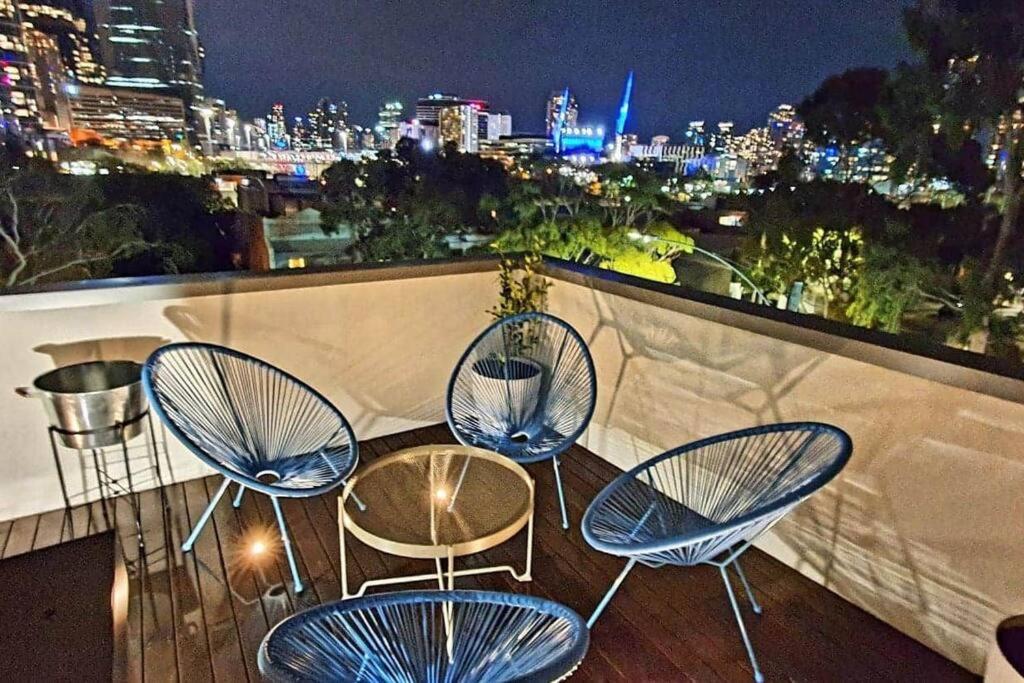墨尔本Flagstaff Hill West Melbourne的阳台上的三把椅子和一张桌子在晚上