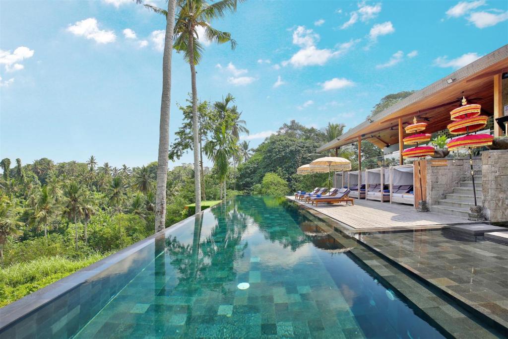 乌布Kaamala Resort Ubud by Ini Vie Hospitality的棕榈树度假村的无边泳池