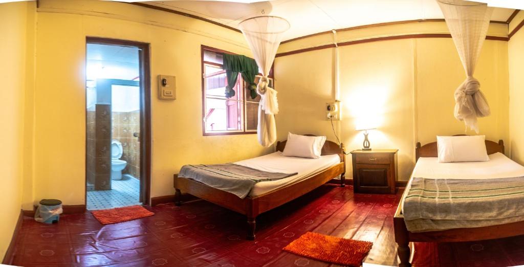 Ban DonsômXaymountry Don Khon City Center Residence and Guesthouse的带镜子的客房内设有两张床的房间