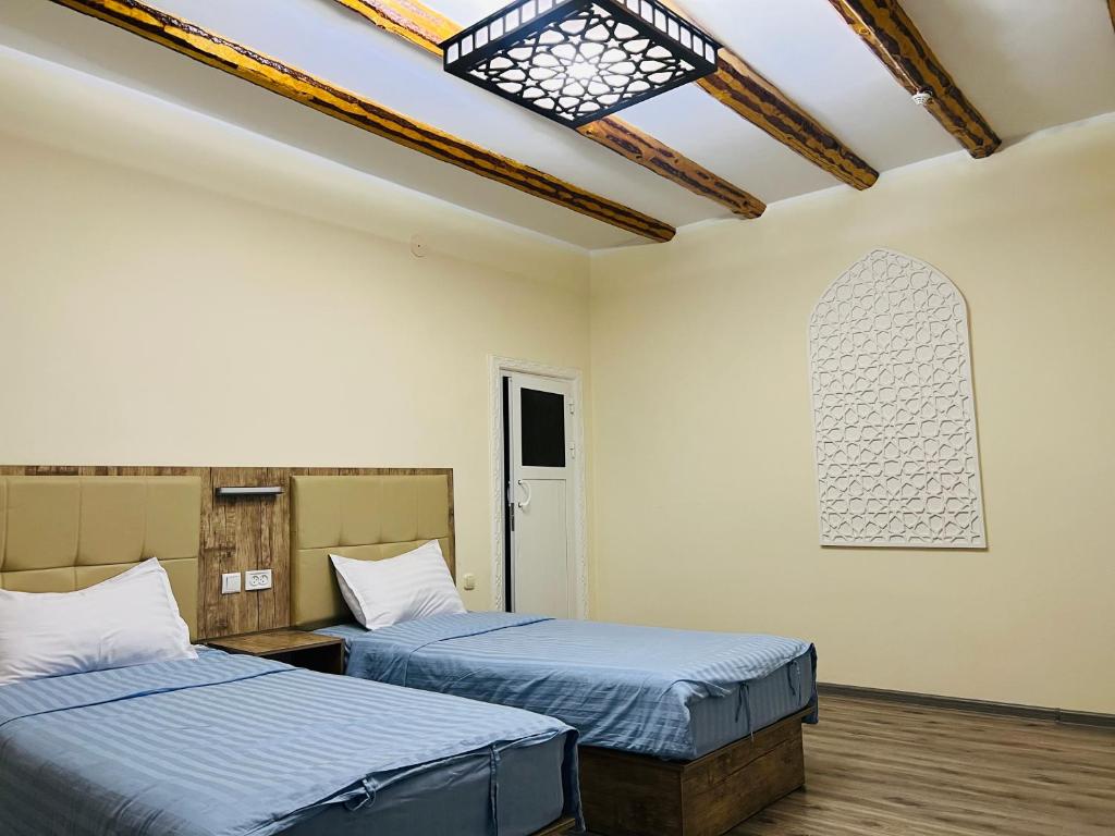 布哈拉BUKHARA HOUSE hotel的客房设有两张床和一面墙上的窗户。