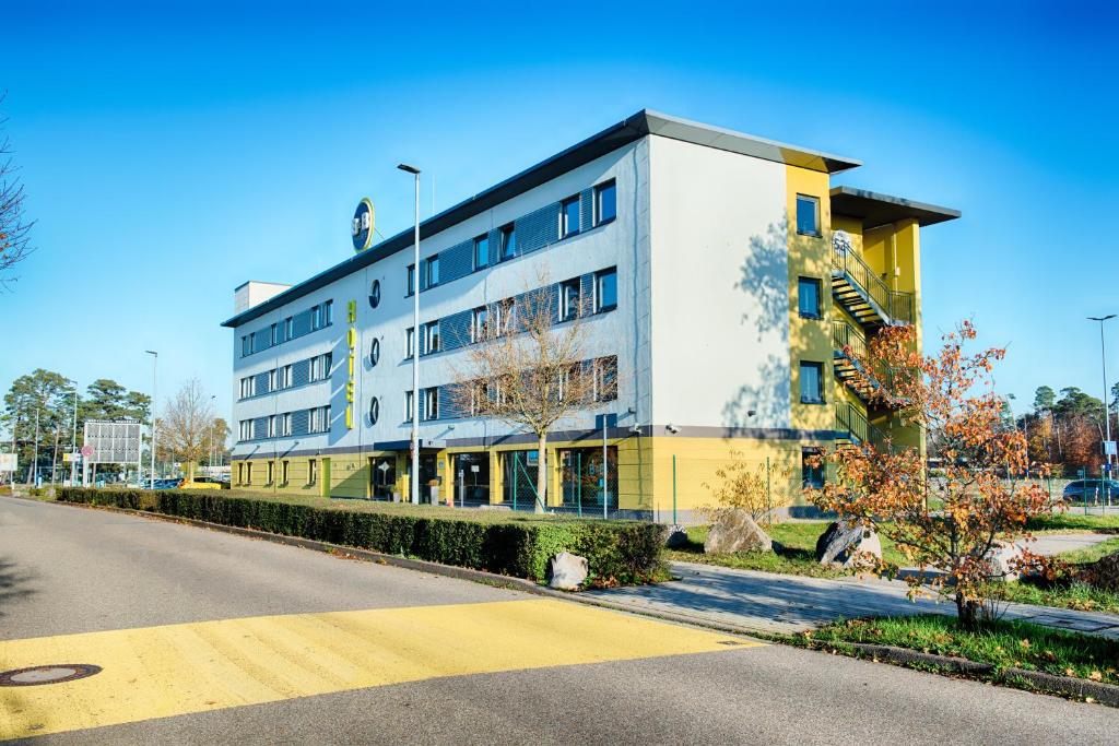 莱茵明斯特B&B HOTEL Baden-Airpark的街道边的白色和黄色建筑