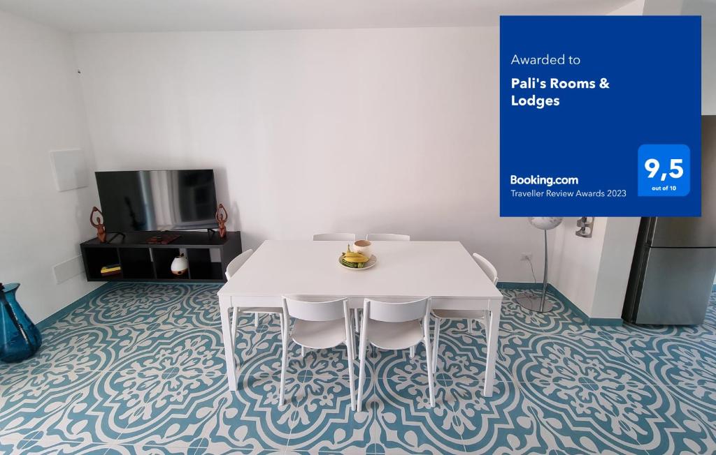 托瑞帕利Pali's Rooms & Lodges的带电视的客房内的白色桌椅