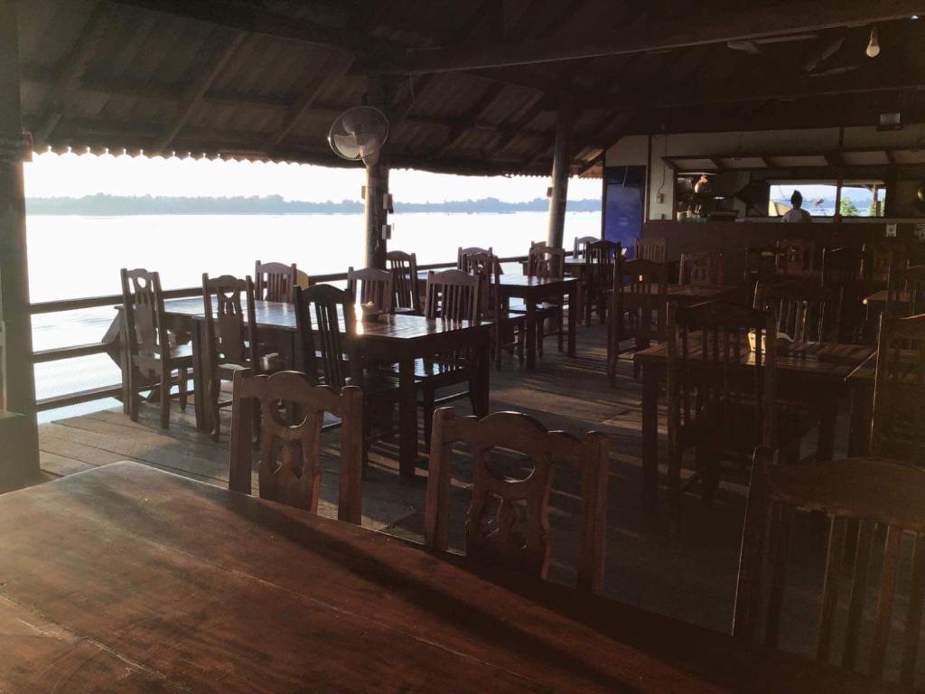 Muang KhôngPon's Riverside Guesthouse的一间带桌椅并享有水景的餐厅
