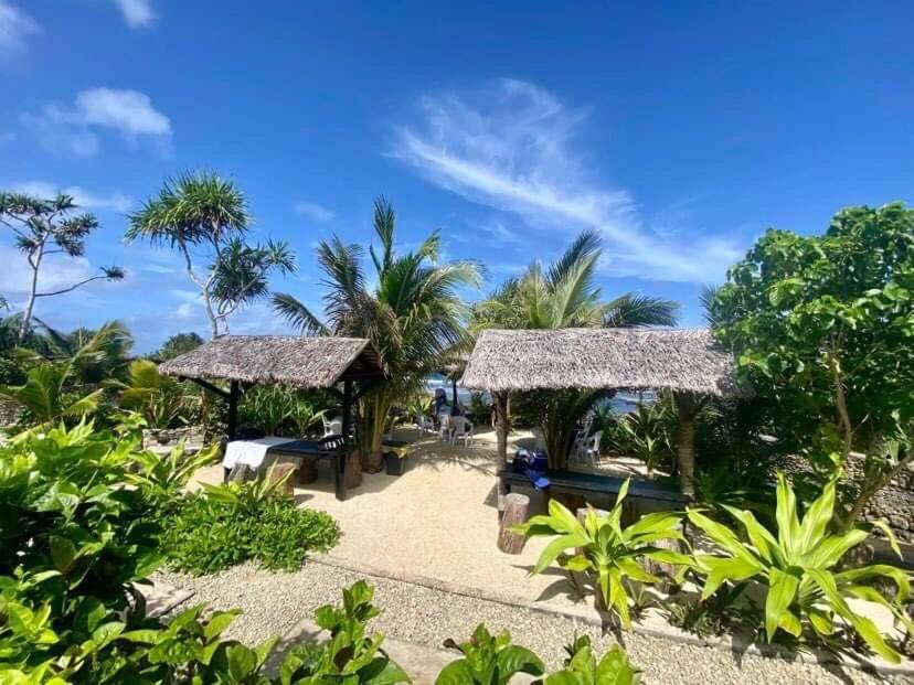 维拉港Banana Bay Beach Club的一个带两个凉亭和棕榈树的度假村