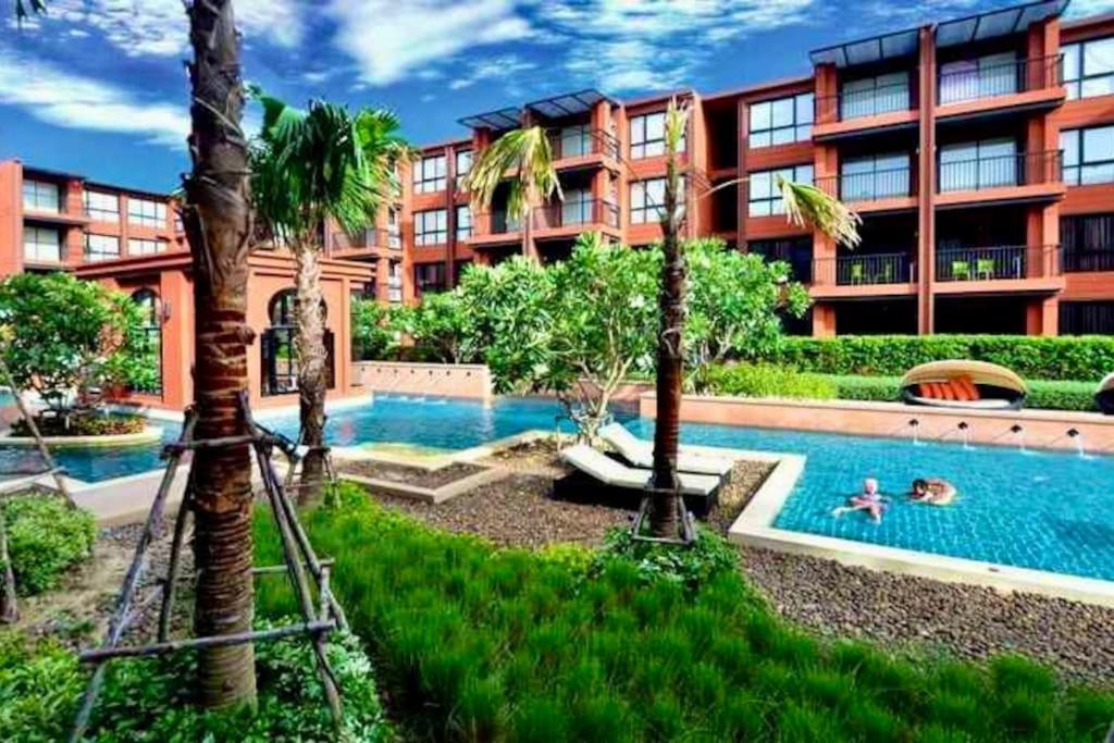 华欣Cozy resort-style condominium的一座拥有游泳池和棕榈树的酒店