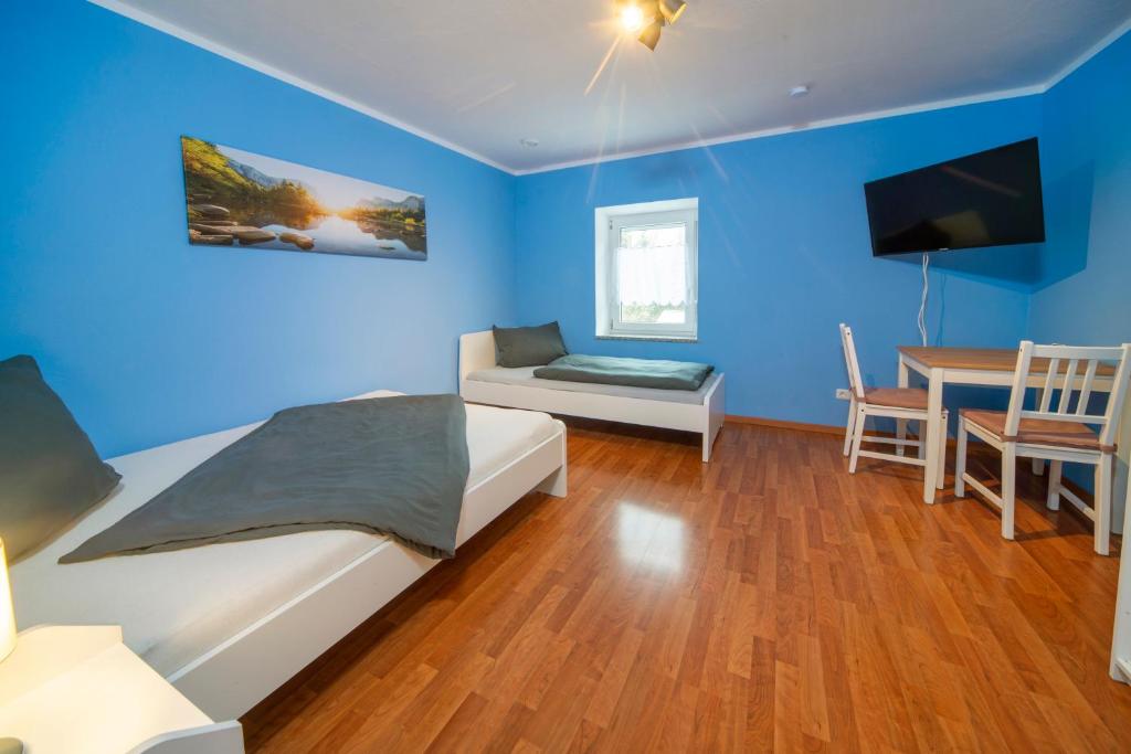 梅明根Apartment - Wohnung Memmingen Nr. 3的一间拥有蓝色墙壁的卧室,配有一张床和一张桌子