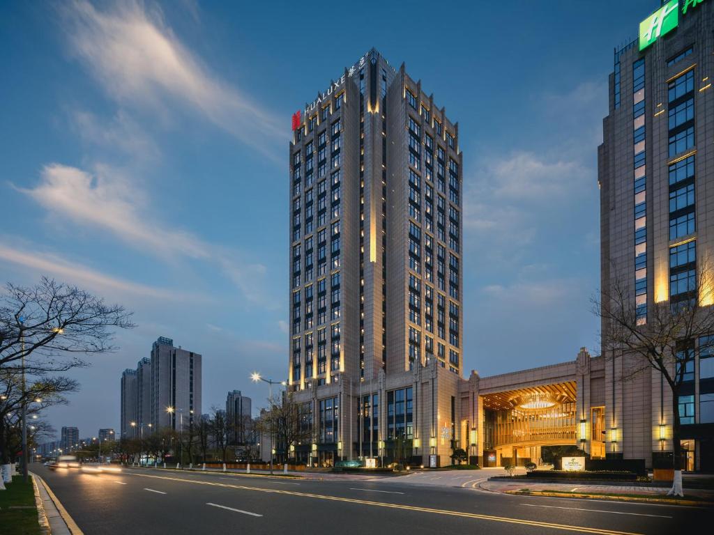 昆山HUALUXE Kunshan Huaqiao, an IHG Hotel - F1 Racing Preferred Hotel的夜幕降临的城市街道上一座高楼