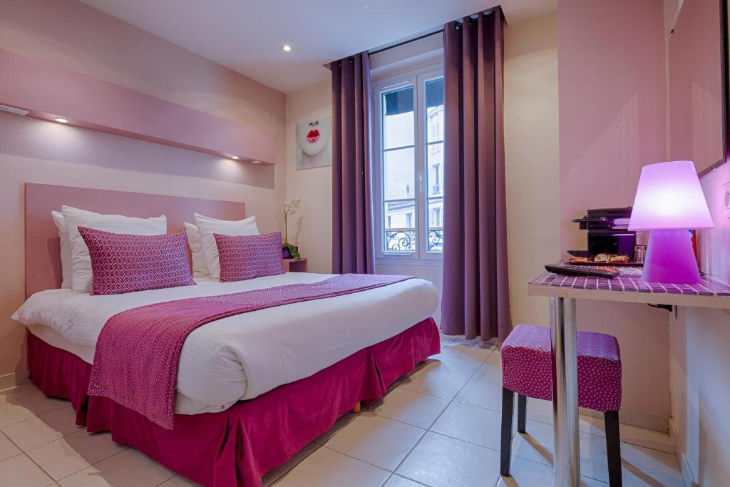 巴黎品客酒店的一间卧室配有一张床和一张带台灯的桌子