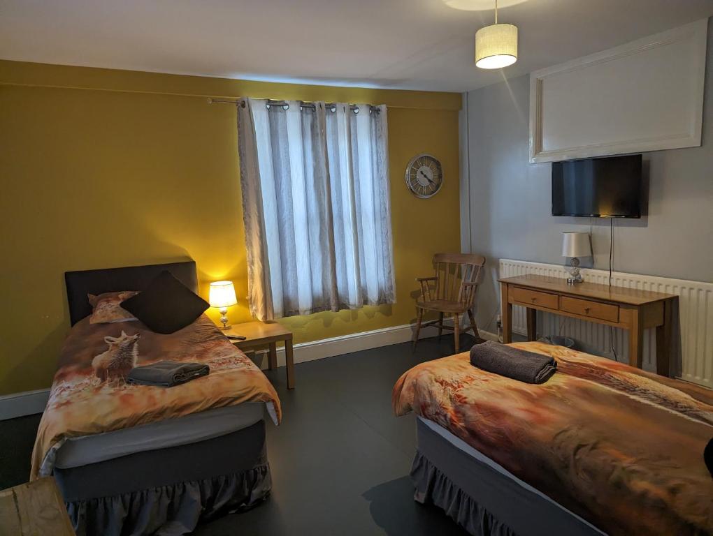布里斯托The Fox的一间卧室设有两张床、一张桌子和一个窗口。