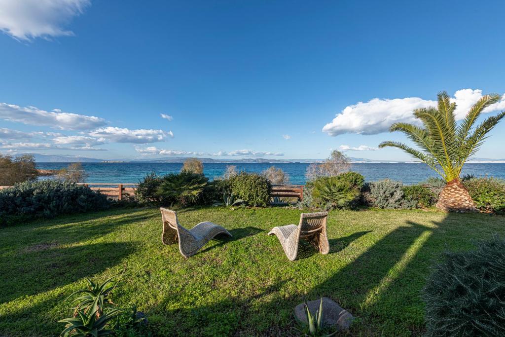 ÁyioiDream House的两把椅子坐在靠近海洋的草地上