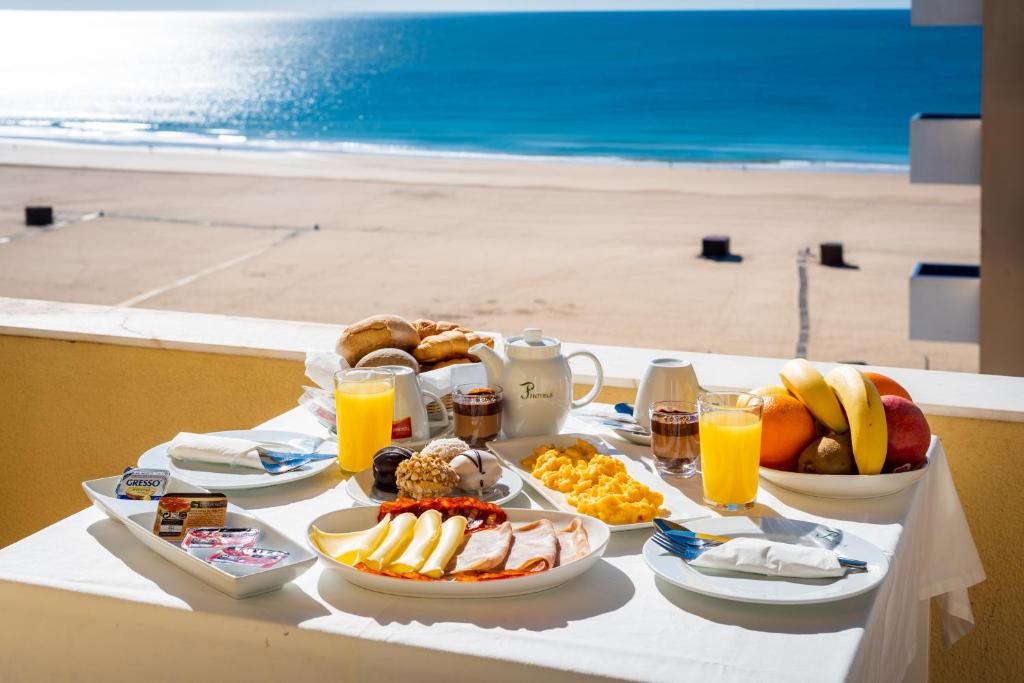 波尔蒂芒阿尔加维圣卡塔里娜酒店的海滩上的餐桌,包括早餐食品和饮料