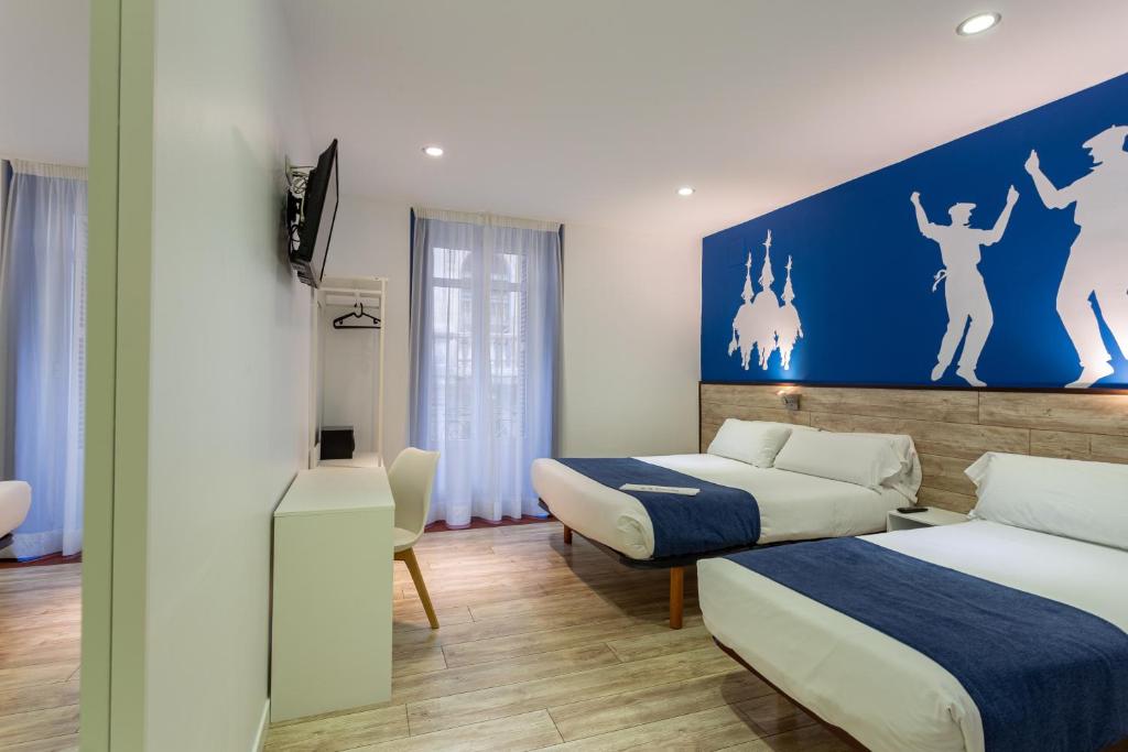 毕尔巴鄂Casual Blue的酒店客房设有两张床和蓝色的墙壁。