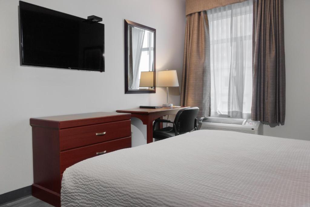 汉密尔顿Premier Inn & Suites - Downtown Hamilton的酒店客房配有一张床、一张书桌和一台电视。