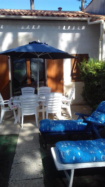 莱马特Talaris La Palmyre的庭院配有白色椅子和蓝色遮阳伞