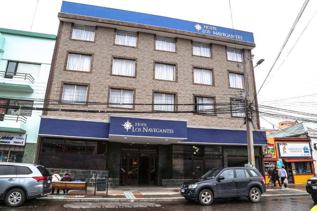 蓬塔阿雷纳斯HOTEL LOS NAVEGANTES的街道上的建筑物,前面有车辆停放