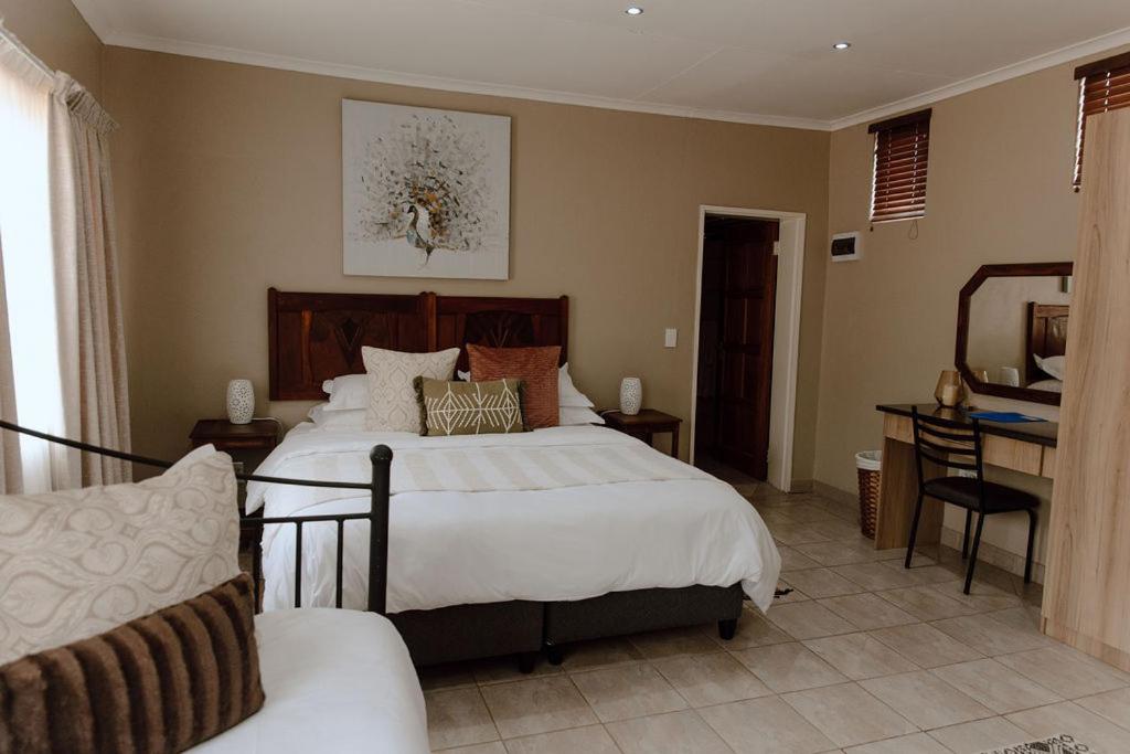 RietfonteinMarjaniek Wedding Venue & Guest House的一间卧室配有一张大床和一张书桌