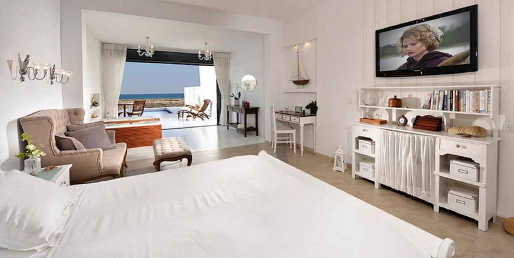 沙韦锡安Yamim Suites On The Beach的一间白色的卧室,配有床和客厅