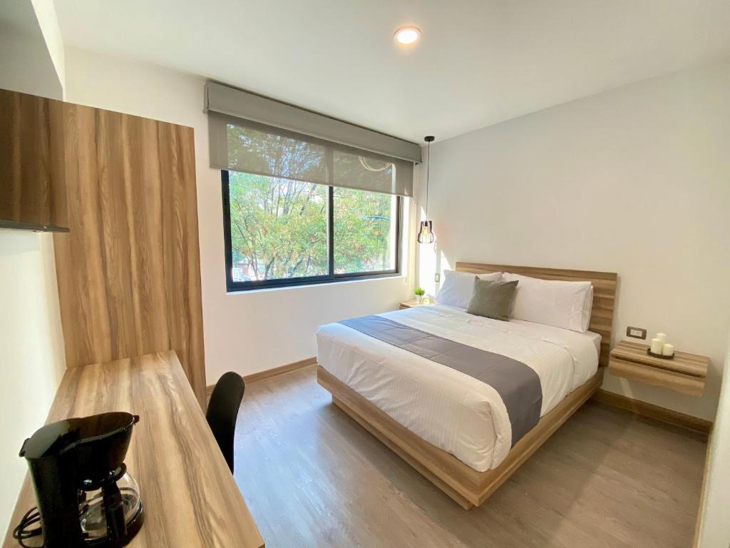墨西哥城Darwin 8的一间卧室配有一张床、一张桌子和一个窗户。