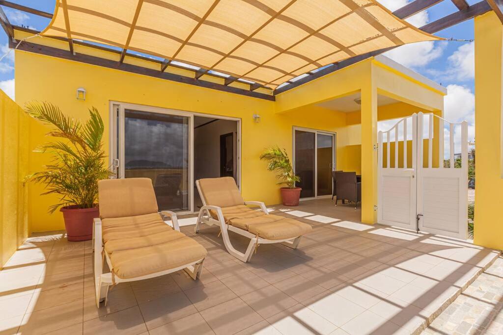South Hill VillageThe Junior Suite's "Palm Studio Apartment"的一个带两把椅子的庭院和黄色的房子