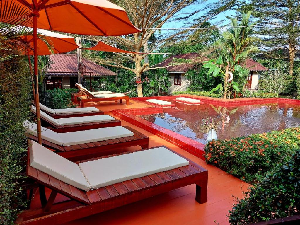 象岛哈雷月亮度假酒店的池塘旁的一组椅子和一把伞