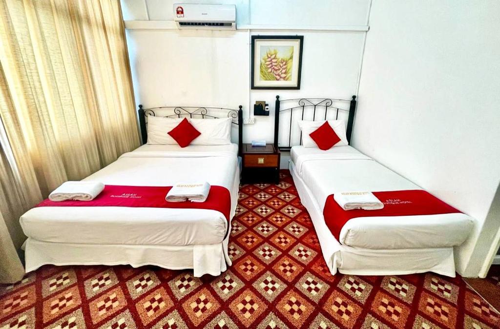 哥打巴鲁ASLAH BOUTIQUE HOTEL的两张位于酒店客房的床铺,配有红色枕头