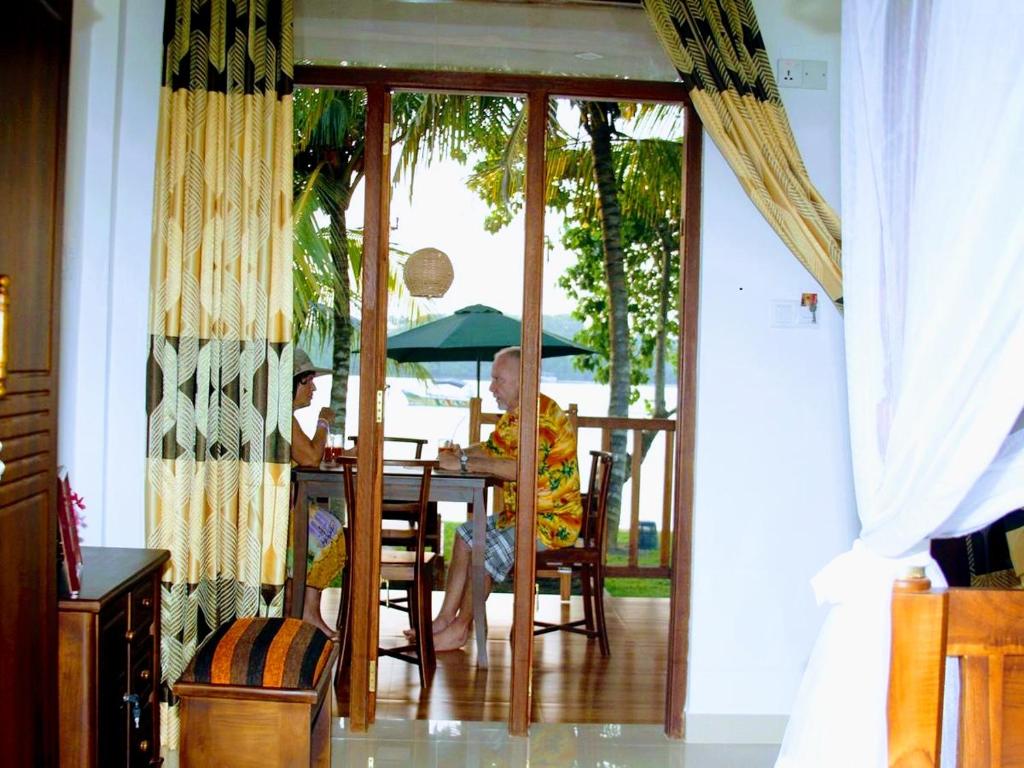 肯克拉Koggala Lake view P&J Villa的坐在桌子上拿着雨伞的人