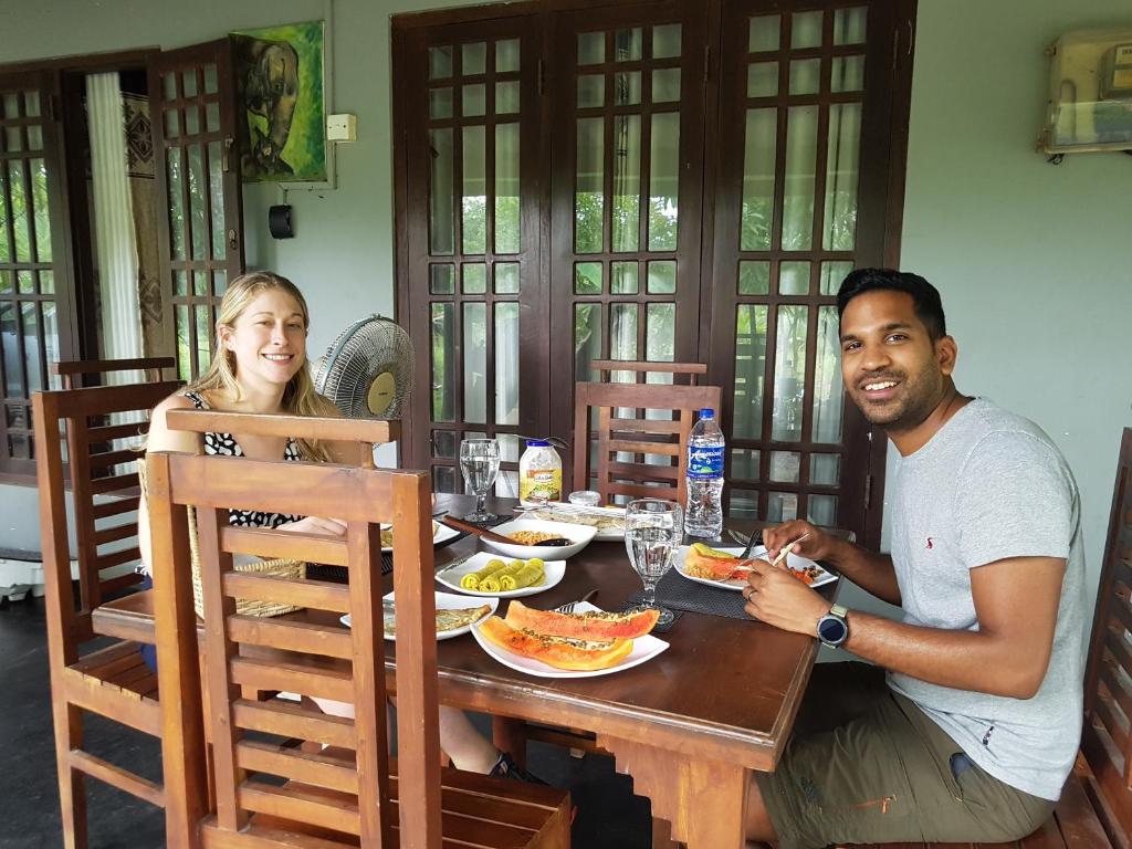维勒珀图Wilpattu homestay by Ceylon group的坐在餐桌旁吃饭的男人和女人