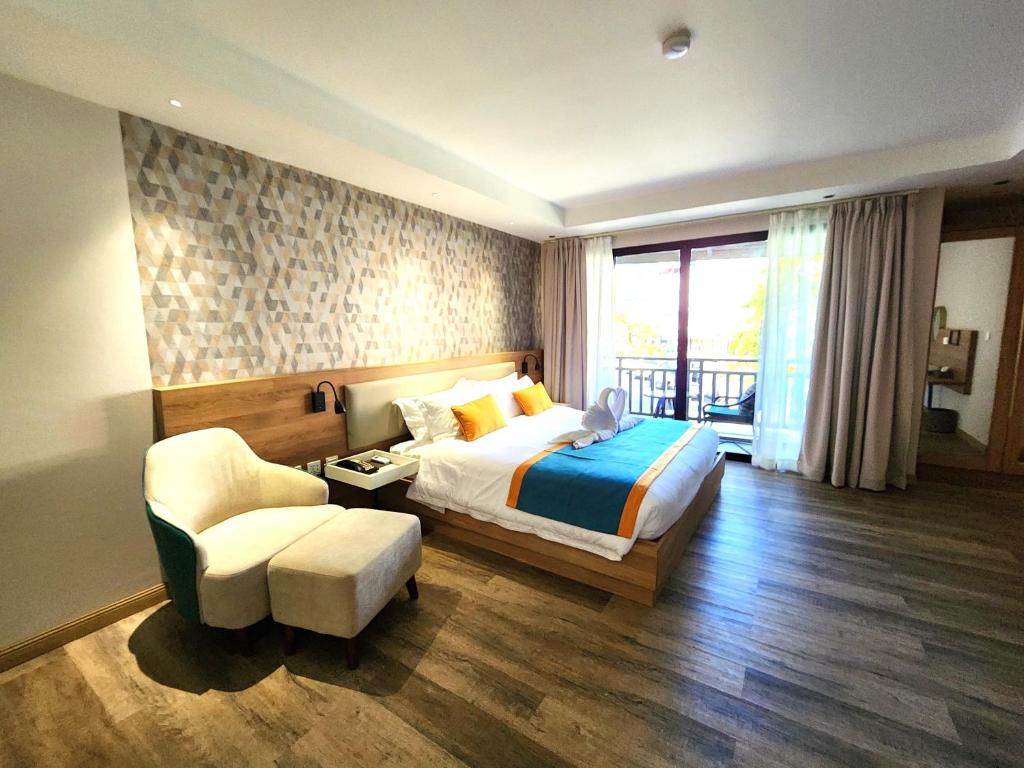 芭东海滩Amalthea Hotel的配有一张床和一把椅子的酒店客房