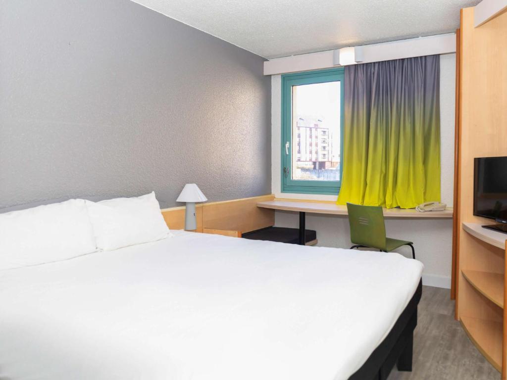 梅斯梅斯中心大教堂宜必思酒店的一间卧室配有一张床、一张书桌和一个窗户。