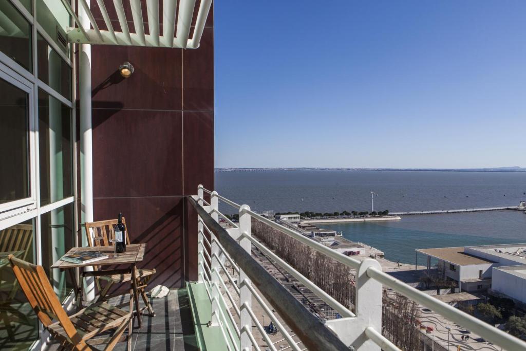 里斯本RENT4REST LISBON PARQUE DAS NAÇÕES 17Th FLOOR RIVER VIEW的一个带桌椅的海景阳台