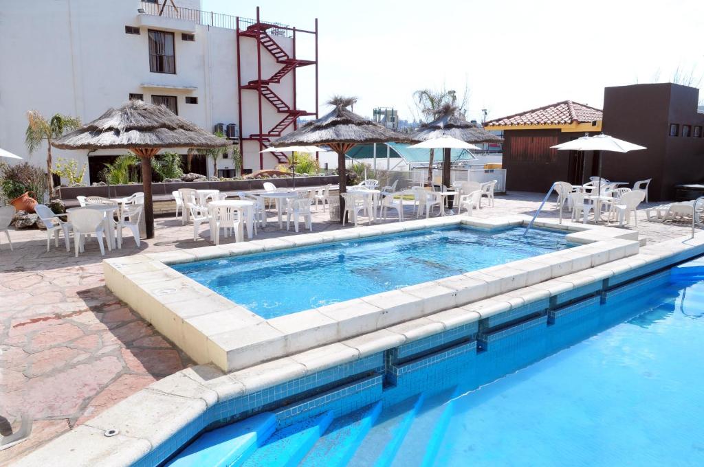 维拉卡洛斯帕兹总统酒店的游泳池配有椅子、桌子和遮阳伞