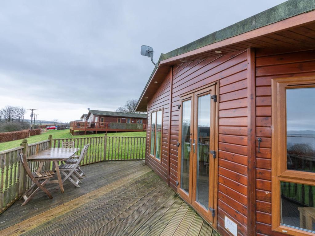 金罗斯Chalet Loch Leven Lodge 4 by Interhome的木甲板上配有桌子和长凳