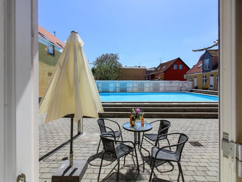 古兹耶姆Apartment Amaia - 500m from the sea in Bornholm by Interhome的游泳池旁配有桌椅和遮阳伞
