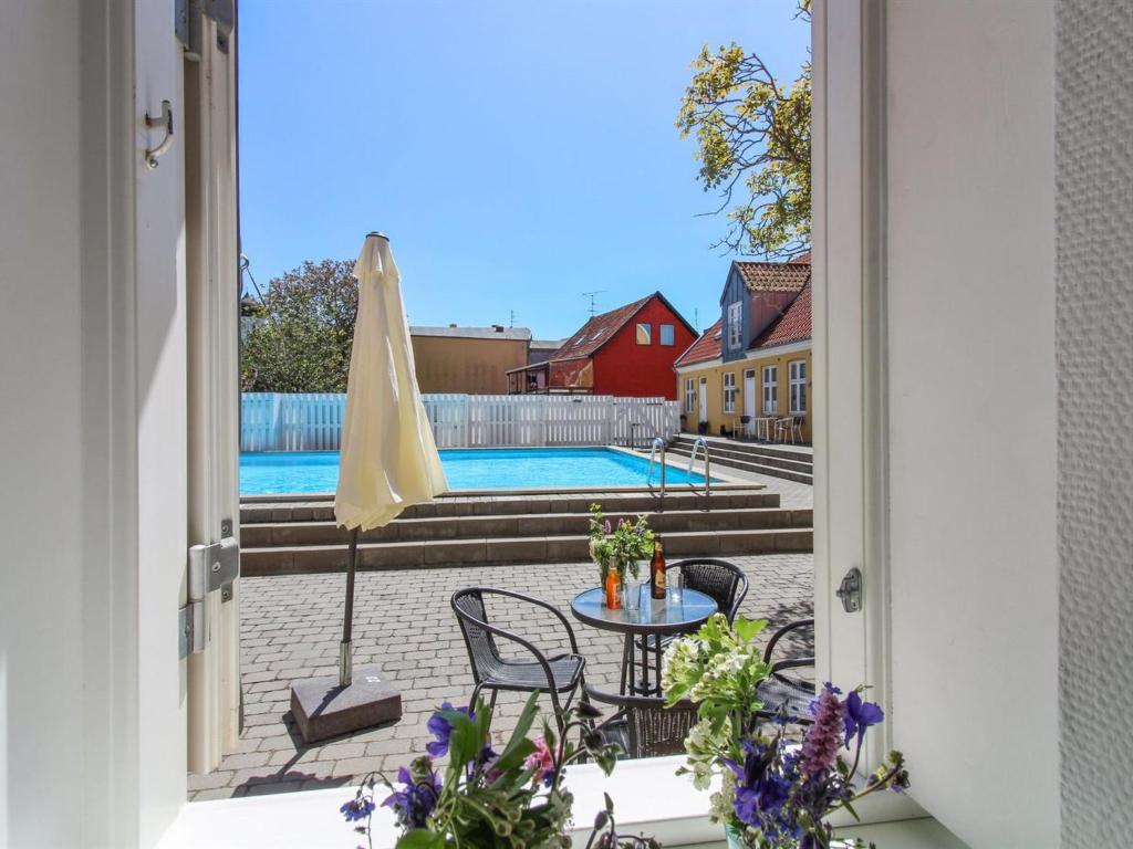 古兹耶姆Apartment Thyrne - 500m from the sea in Bornholm by Interhome的通往带桌子和遮阳伞的天井的开放式门