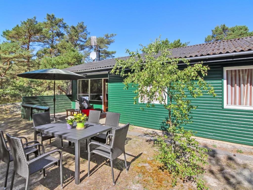 维斯特索马肯Holiday Home Michel - 300m from the sea in Bornholm by Interhome的桌椅和遮阳伞位于房子前