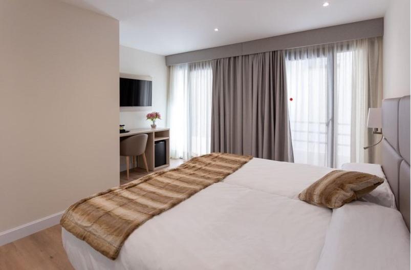 坎普罗东Hotel SAIOLA的卧室在窗户前配有一张白色大床