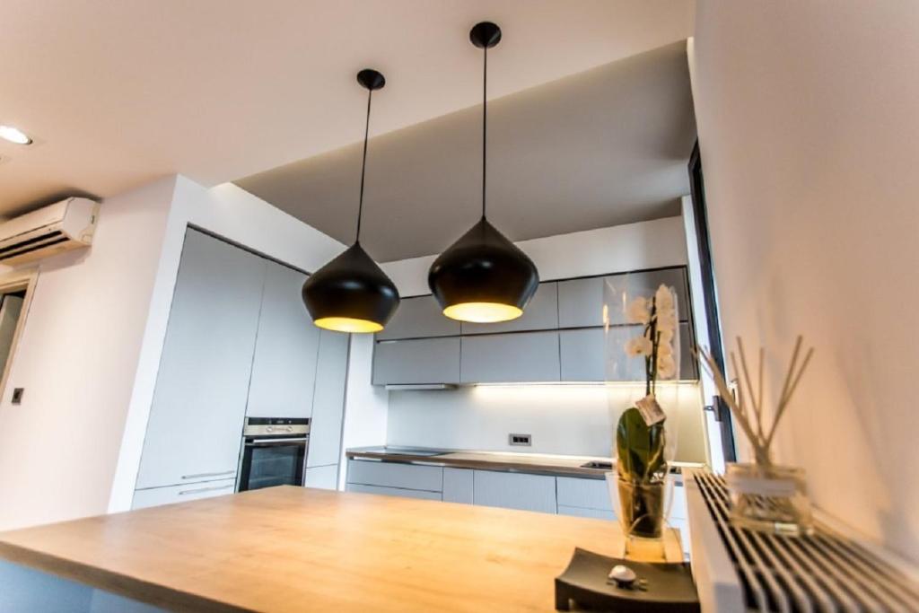 布加勒斯特Anvers Apartament的厨房配有2盏吊灯和一张木桌