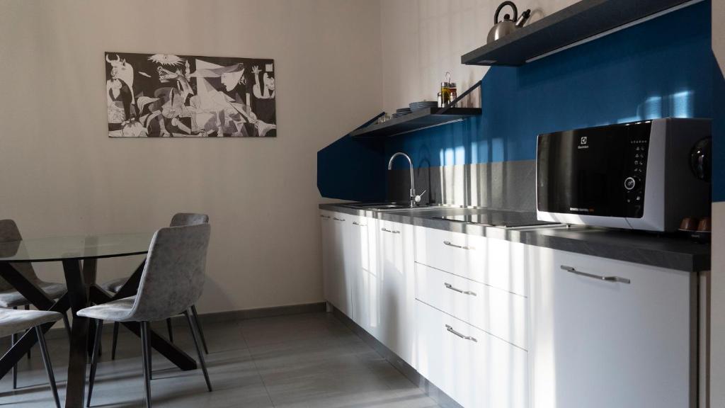 卡塔尼亚Etna Suite Design Apartments的厨房配有白色橱柜和带微波炉的桌子。