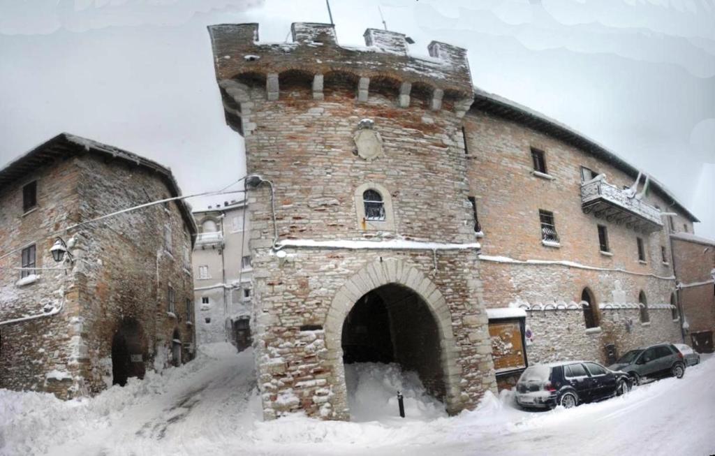 福萨托-迪维科Appartamento nel Castello presso Gubbio的一座大砖砌建筑,有一座塔楼,下雪