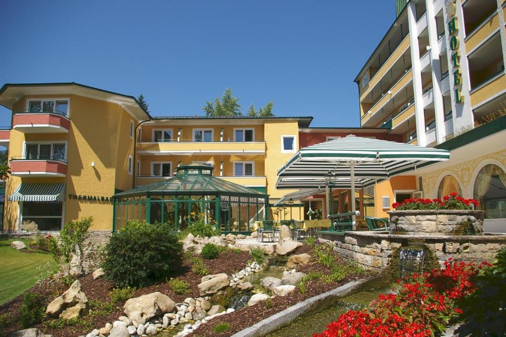 巴特法兴格公园酒店的一座建筑,前面有一个花园,上面有遮阳伞