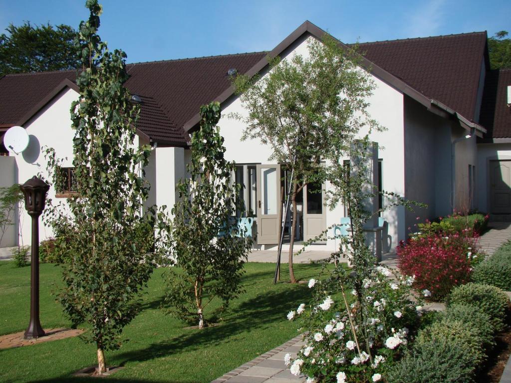 伊登维尔Bergliot Guest House的院子里有树木和白色花朵的房子