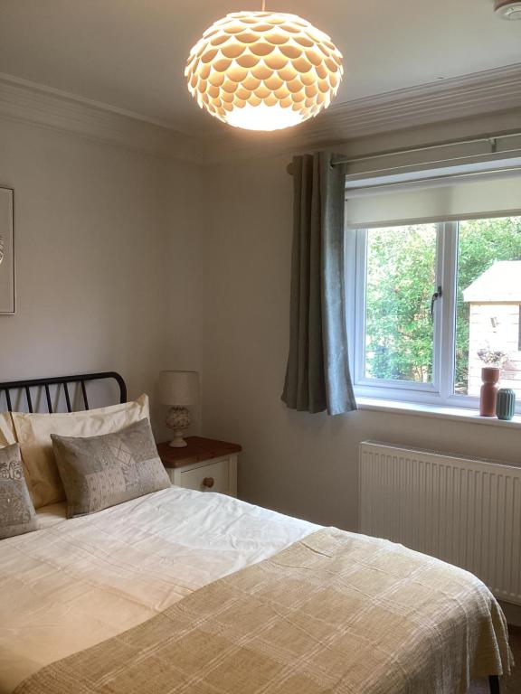 灵伍德Forest Heath Holidays - Denphyl的一间卧室配有一张床和一个吊灯