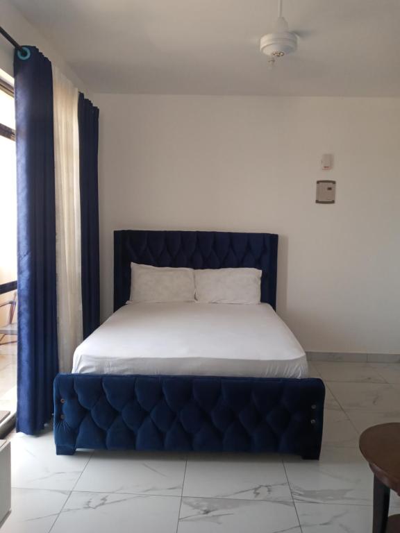 蒙巴萨Amber Apartment的一张带蓝色簇绒床架的床