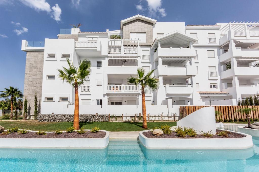 莫特里尔Homity Exclusive Playa Granada Beach & Golf - Marina Golf的一座大型白色建筑,在游泳池前种有棕榈树