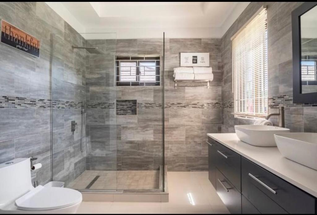 欧丘里欧Luxurious Villa Royale- 5 min drive to Ocho Rios的带淋浴、两个盥洗盆和卫生间的浴室