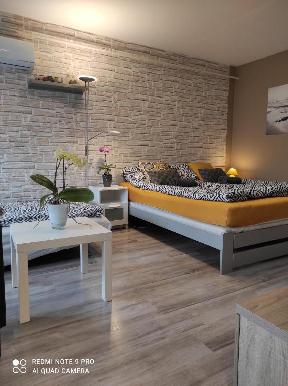 考波什堡Baross apartman的一间卧室设有两张床和砖墙