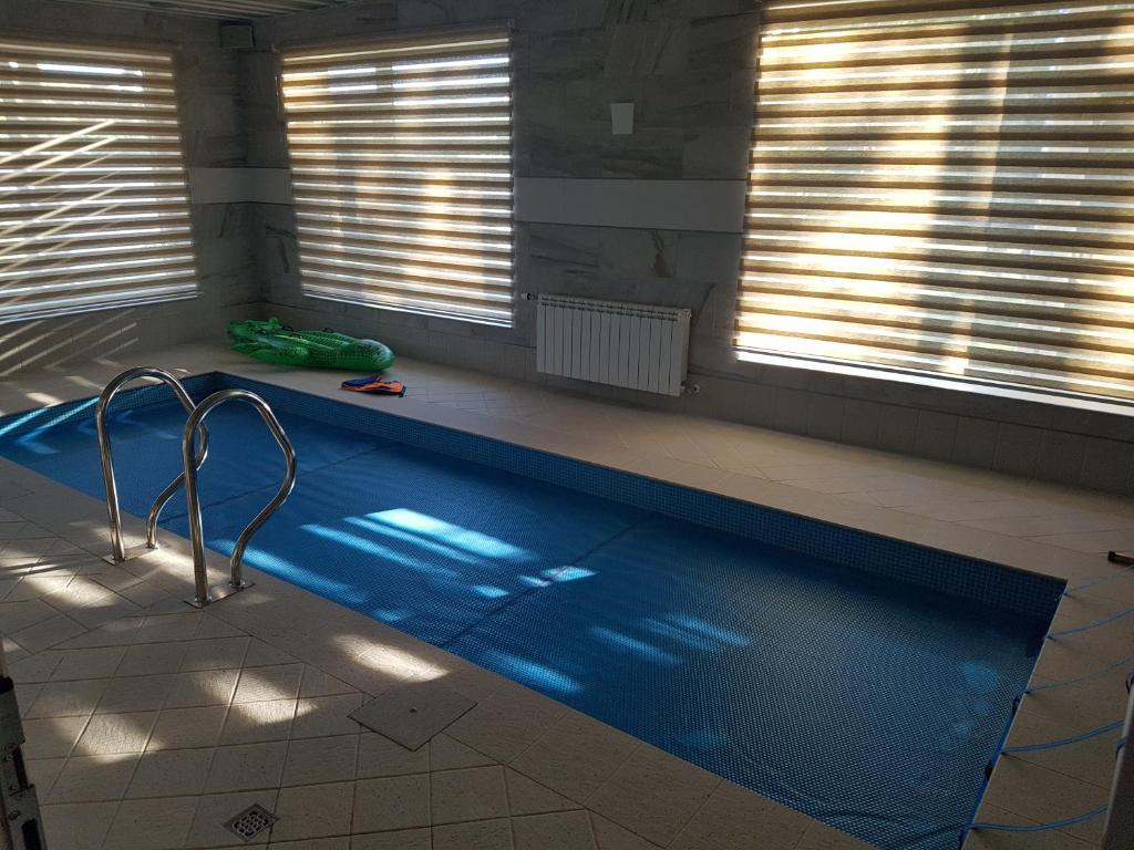 Mežnoras holiday house的一个带两个窗户的房间的游泳池