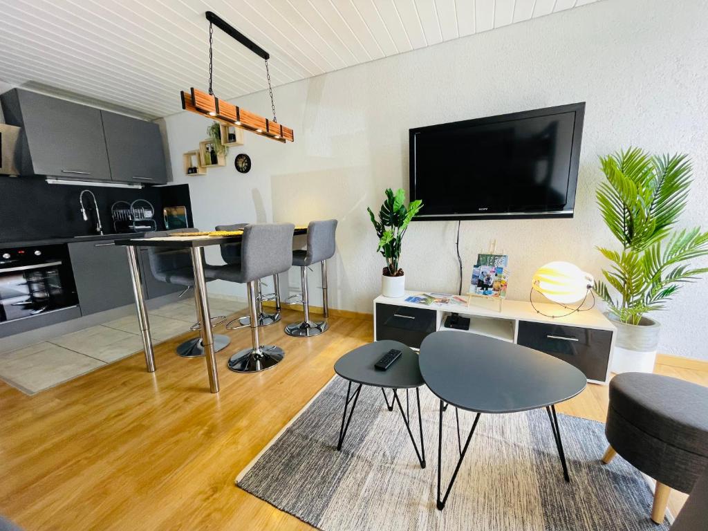 梅塔比耶Au Doubs Village的客厅配有桌椅和电视。