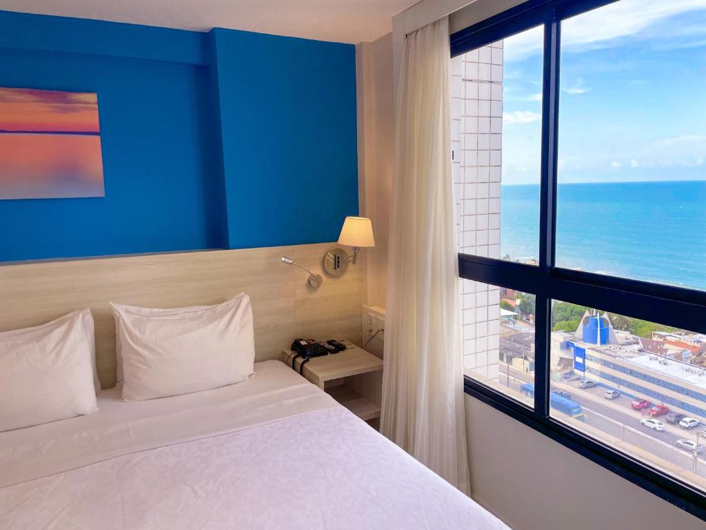纳塔尔Janastí Suítes Praia de Ponta Negra的酒店客房设有一张床和一个大窗户
